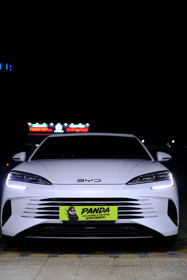 White BYD with a Panda Car Wash plate at night