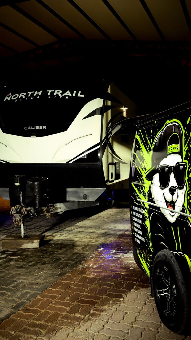 North Trail caravan beside the Panda Car Wash van at night