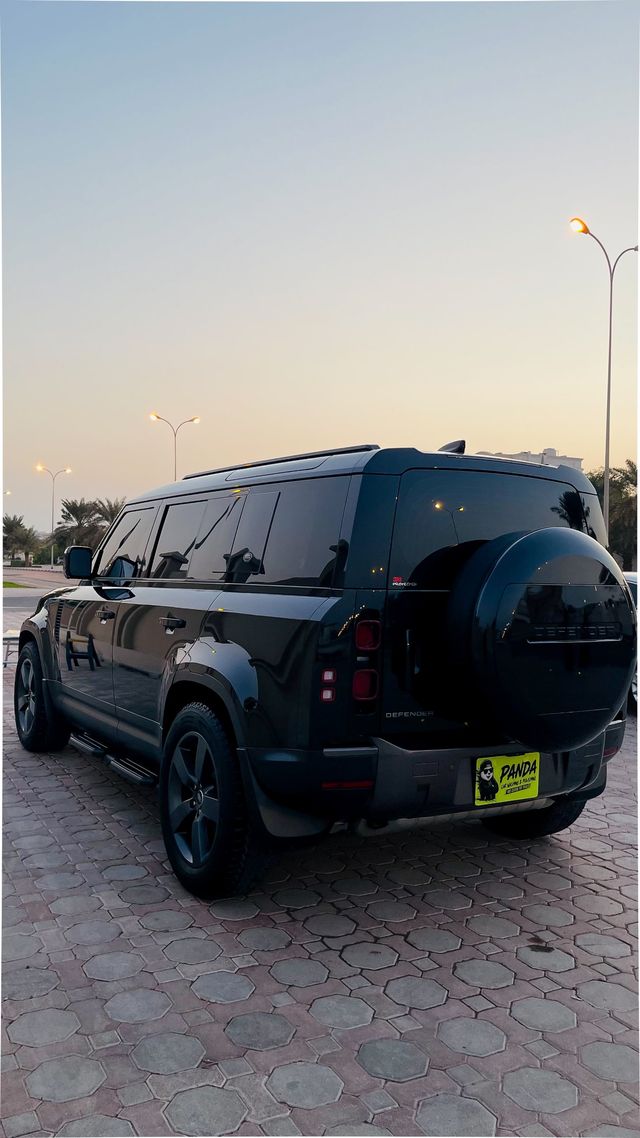 Black Land Rover Defender with a Panda Car Wash plate at sunset