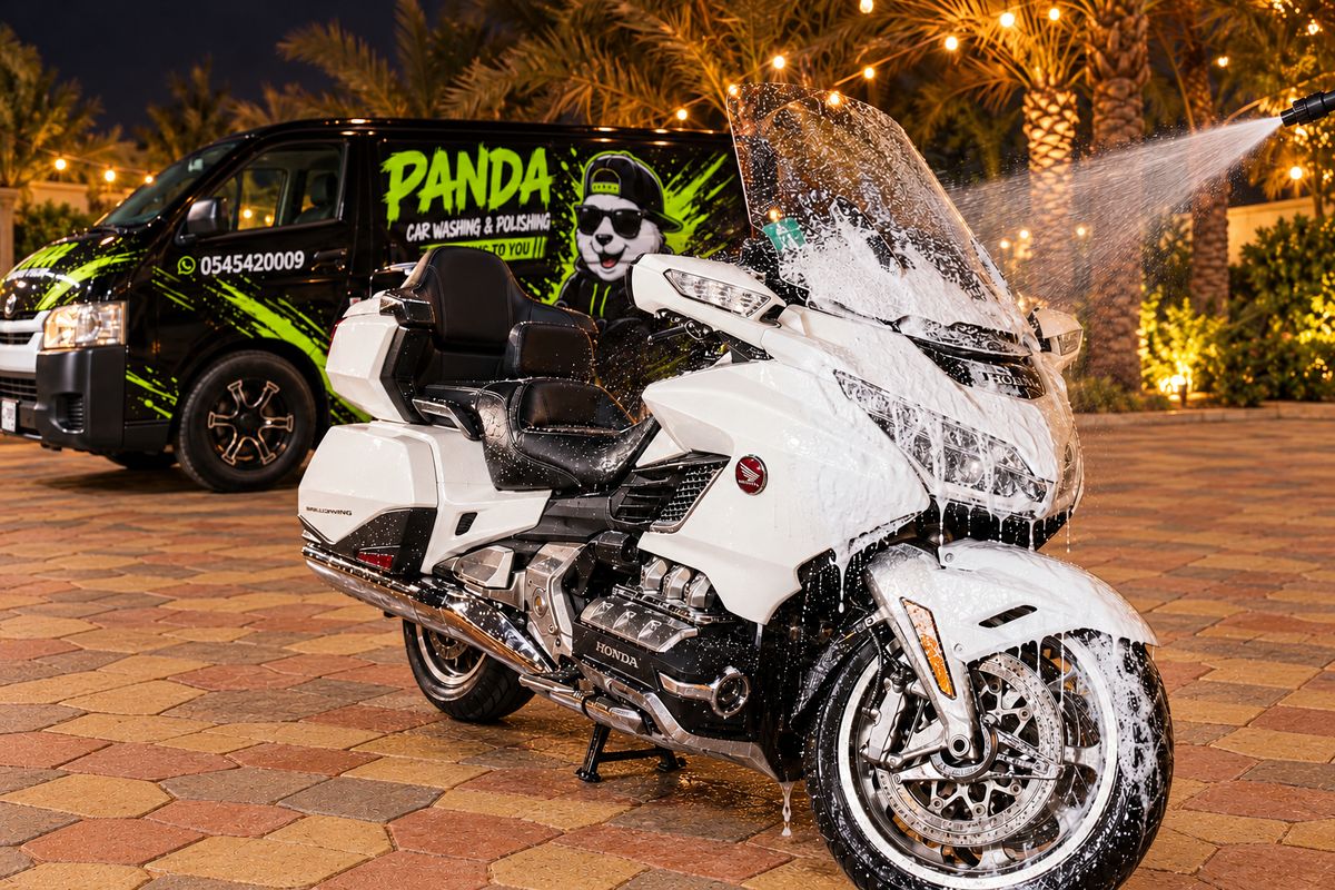 White Honda Gold Wing covered in foam during a night wash, with the Panda Car Wash van behind