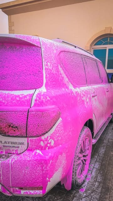 White SUV covered in pink coloured foam during a wash outside a villa in Ajman